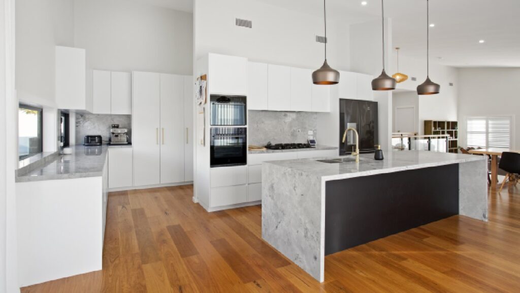 Modern open-plan kitchen with marble island, pendant lighting, and timber flooring—an elegant example of custom kitchens designed for both functionality and style.