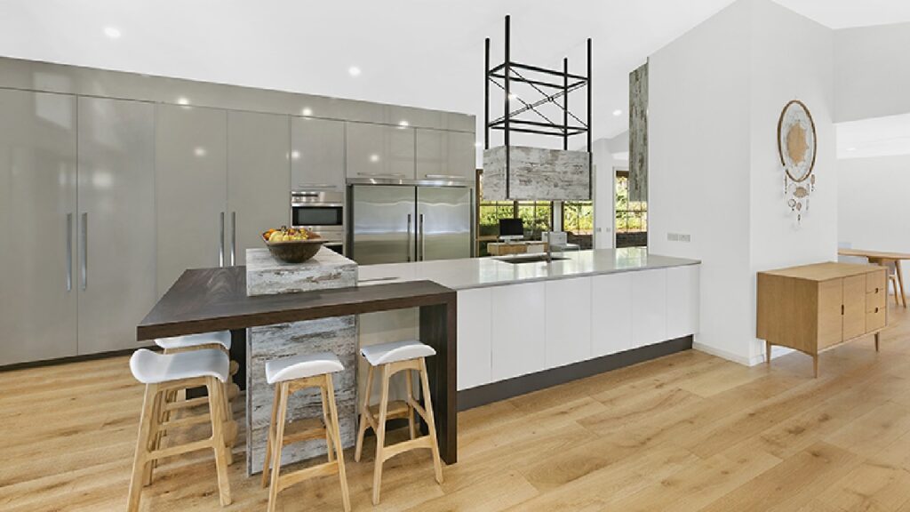 An example of open plan ideas for industrial kitchens. Open plan industrial kitchen with minimalist cabinetry, stainless steel appliances, and layered island bench design that maximises space and flow between living zones—the perfect example of open plan ideas for industrial kitchens.