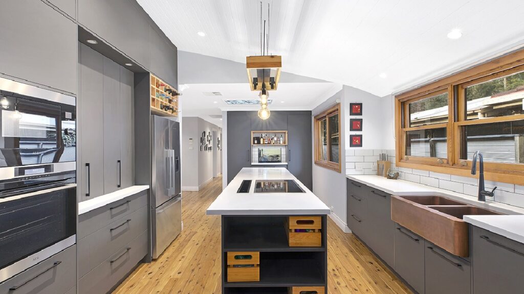 Industrial kitchen with matte grey cabinetry, timber flooring, copper farmhouse sink, and minimalist pendant lighting—showcasing modern industrial kitchen ideas with a functional island, integrated appliances, and a blend of raw textures and clean lines.